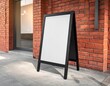 © CHOISH - 벽돌 건물 앞 인도 위에 놓인 블랙 프레임 A자 스탠드 보드 Black metal frame A-frame sandwich board standing on sidewalk in front of brick building