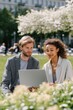 © Iryna - Male and female adults with laptop in outdoor park setting