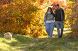 © nuzza11 - A young couple in love walks through the park with their pet. The lovers enjoy the golden autumn scenery.