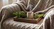 © Zhanna - Warm cup of coffee on wooden tray with pine branches on cozy sofa