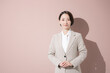 © kapinon - ピンク背景でカメラ目線で立つスーツの女性