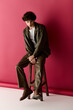 © LIGHTFIELD STUDIOS - Stylish man poses confidently against a vibrant red backdrop in contemporary fashion