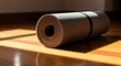 © Genesistor Studio - A rolled-up yoga mat rests on a polished wooden floor, bathed in warm sunlight streaming through a window.