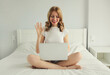 © rohappy - Happy woman working on laptop greets communicates with friends via video call at home