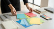 © Volha - Person selecting colorful paper swatches on desk