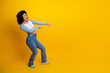 © deagreez - Joyful woman in casual attire dancing against a vibrant yellow background, expressing excitement and happiness