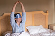 © ADDICTIVE STOCK - Woman stretching in bed wearing sleep mask and pajamas