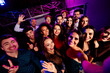 © deagreez - Group of smiling party goers at a vibrant club posing for a selfie together during a lively event