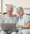 © Daniel - Pretty elderly 70s grey-haired couple resting on couch in living room hold on lap laptop watching movie smiling enjoy free time, older generation and modern wireless technology advanced users concept