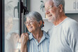 © Daniel - Happy bonding loving middle aged senior retired couple standing near window, looking in distance, recollecting good memories or planning common future, enjoying peaceful moment together at home.