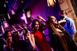 © deagreez - Energetic party scene of friends dancing at a nightclub with neon lights smiling crowd and festive vibe at a big event