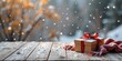 © Cherrin - Gift box on snowy wooden table with a wintery background and falling snowflakes.