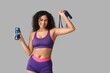 © Pixel-Shot - Sporty young African-American female coach with jumping rope and water bottle on white background