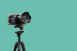 © Pixel-Shot - Professional camera on tripod against turquoise background