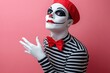 © Tatyana - Person in mime makeup and costume with white face paint, red hat, red bow tie, and black-and-white striped shirt posing against a pink background with a confident expression