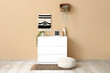 © Pixel-Shot - Chest of drawers, pouf and houseplants near beige wall in interior of living room