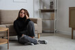 © Pixel-Shot - Sad young woman sitting on carpet at home