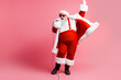 © deagreez - Santa performs on pink backdrop wearing red suit cape and hat singing into a microphone for festive holiday promotion