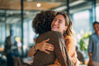© EricMiguel - Joyful colleagues embracing in a bright modern office — two women share a warm hug, celebrating reunion, teamwork, friendship and workplace connection.