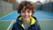 © miss irine - Smiling boy with curly hair standing outside. Kid poses in warm jacket. Happy preteen with brown eyes looks at camera. Person has good mood. Child on sport playground in autumn.
