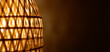 © Jam - Illuminated bamboo wicker lampshade casting warm decorative light with geometric pattern on brown background for cozy interior design concept