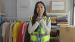 © Krakenimages.com - Young chinese woman in reflective vest volunteering in an indoor charity center surrounded by donated clothes for community service.