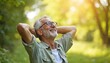 © miss irine - Elderly man with glasses relaxes outdoors with hands behind head, smiling. Mature male enjoys peaceful nature, sunshine, fresh air, contemplating life in park, feeling happy. Active retirement,