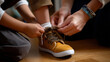 © Laura - Faceless hands helping a child tie their shoelaces before the shoot, nurturing gesture in warm tones, with copy space
