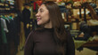 © Krakenimages.com - Woman smiling face with full lips in clothing store with warm lighting and wooden racks; happiness confidence.