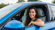 © daniy - Joyful woman smiling while driving her new blue car on a sunny day