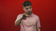 © Krakenimages.com - Man with intense gaze leaning forward pointing finger against red studio wall; challenge authority defiance.