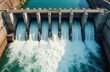 © Pete - Aerial view of massive concrete hydroelectric power dam. Water flows strongly from multiple open gates into turbulent river below. Station generates clean electricity, eco friendly energy source.