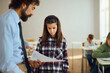 © Goran - Sad elementary student talking to teacher while taking test results on a class in the classroom.