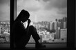 © kieferpix - Silhouette of a woman sitting by a window city apartment, showing sadness and emotional struggle. Represents depression, anxiety, loneliness, and mental health challenges