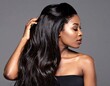 © Bojes - A side profile of a woman with long, dark, wavy hair. She is touching her hair, looking downward. She has a strapless top