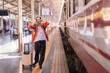 © Tj - Man standing on a train station platform, holding his head in frustration, feeling stressed and anxious about missing his train while his suitcase rests beside him