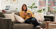 © Malik25/peopleimages.com - Woman, phone and thinking with coffee on couch, texting or smile with online dating chat in home. Person, smartphone and decision with cup, relax and mobile app for social media on sofa at apartment