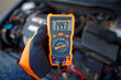 © Tricky Shark - Man testing alternator charge and battery voltage with handheld diagnostic tool while car engine idles seasonal check for automotive electrical system repair maintenance and safe winter driving. 14v