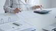 © volha_r - White calculator is on financial documents on the office desk, with an accountant taking notes, emphasizing accounting, finance, and tax preparation, close up. Audit and taxes concept