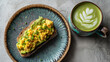 © Shahazadi - Overhead shot of avocado toast with scrambled eggs and a matcha latte on a textured surface