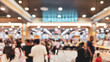 © Achmad - blurry image of a busy interior of a supermarket, the ambiance showing the self-service model in action with numerous people shopping in the aisles.