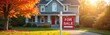 © miss irine - House for sale on autumn day. Real estate market sign in yard. Tree with orange leaves near home. Sun shines on residential property lawn. Buying or selling opportunity.