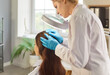 © Studio Romantic - Portrait of young female trichologist or dermatologist doctor examining female patients hair condition under lamp in medical clinic or in beauty salon. Hair loss and trichology concept.
