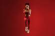 © Prostock-studio - A fitness model demonstrates an impressive jump in a striking red outfit. The energetic pose highlights strength and agility in a captivating setting filled with bold color.