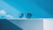 © Wattana - A pair of sunglasses with a blue frame and blue lenses on a white surface with a blue background.