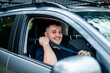 © Austockphoto - An adult man in his thirties is smiling while fastening his seatbelt in a parked car.