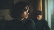 © Jay - Young woman looking out a rainy window while a man stands behind her symbolizing emotional distance