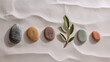 © Karen - Pebbles in size order on sand with leaf, growth progression concept, calm earthy zen aesthetic