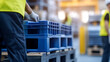© A2Z AI  - Worker in warehouse moving stack of blue plastic pallets. Focus on pallets, conveys industrial efficiency, logistics, and workplace safety. Modern warehouse environment.