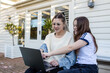 © Austockphoto - Mother working on her laptop in the garden with her tween daughter sitting beside her
